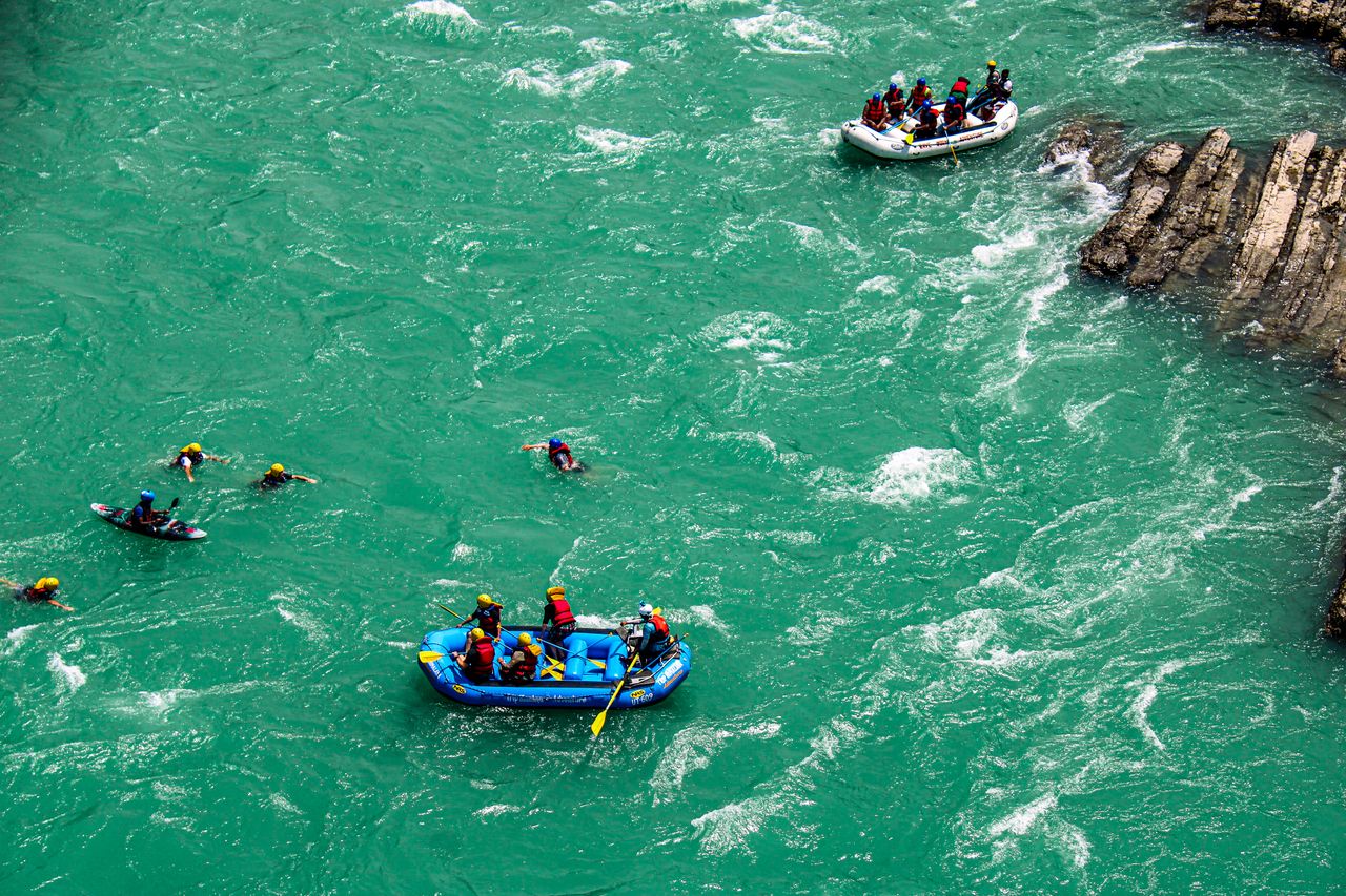 Groups enjoying an exhilarating river rafting and swimming adventure in turquoise waters.